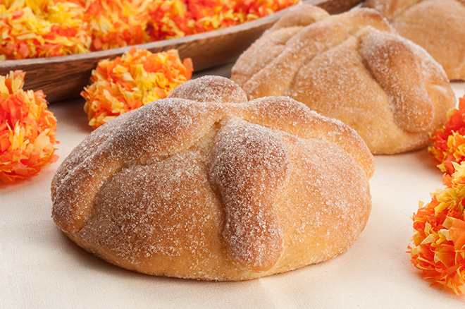 Round sugar-coated 'pan de muerto' bread with orange marigold flowers.
