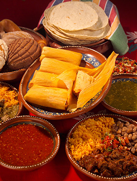 Traditional Mexican meal with tamales, salsas, bread, and tortillas.