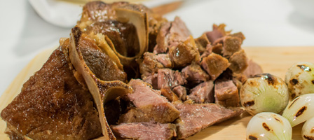 Close-up of roasted meat and grilled onions on a cutting board.