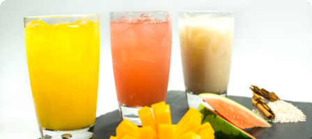 Three glasses with yellow, pink, and beige beverages.